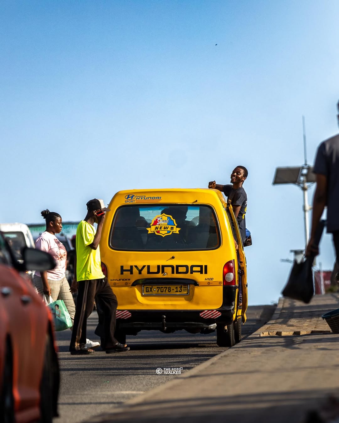 A trotro mate collecting fares inside a yellow trotro