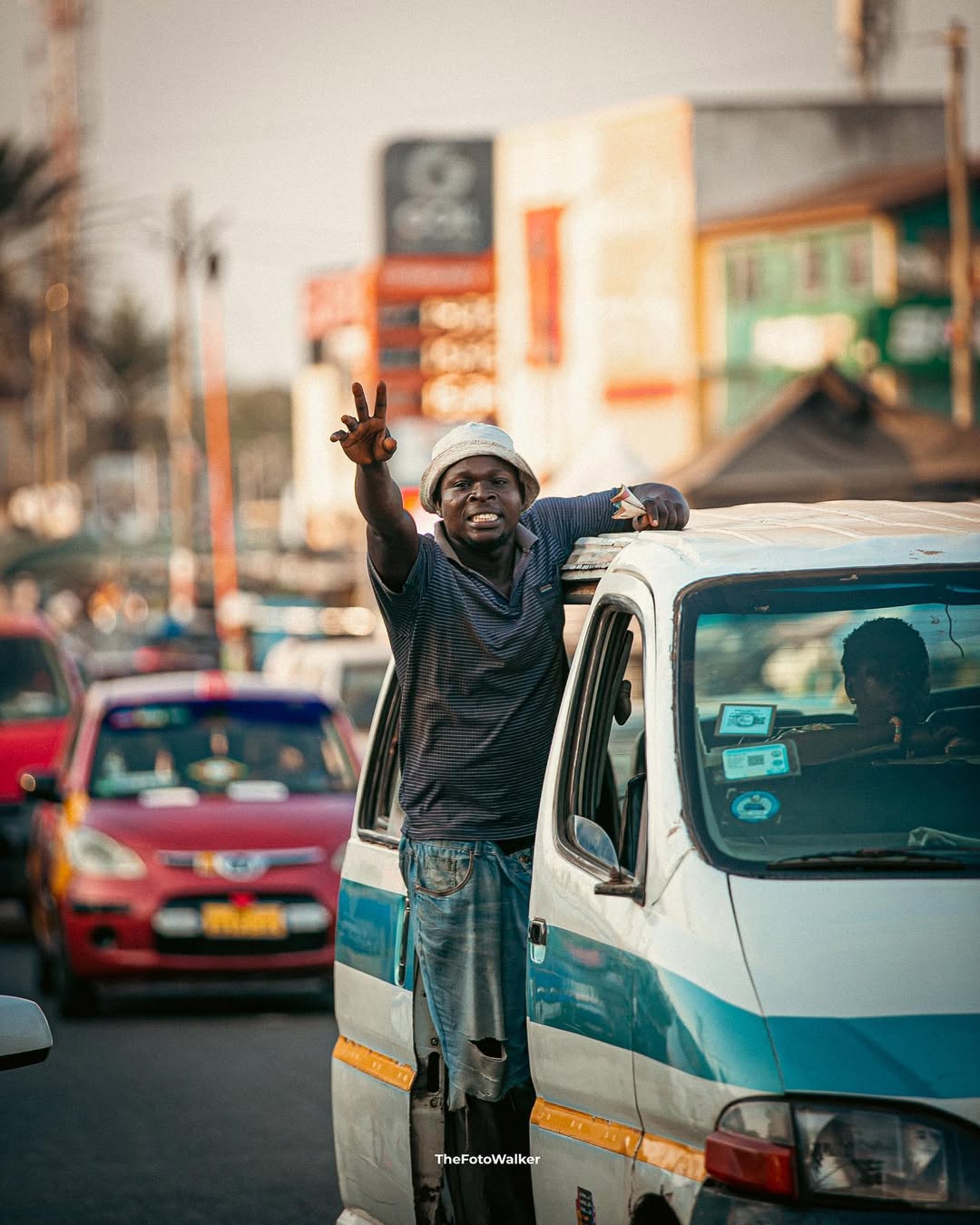 A trotro mate leaning out and shouting the destination